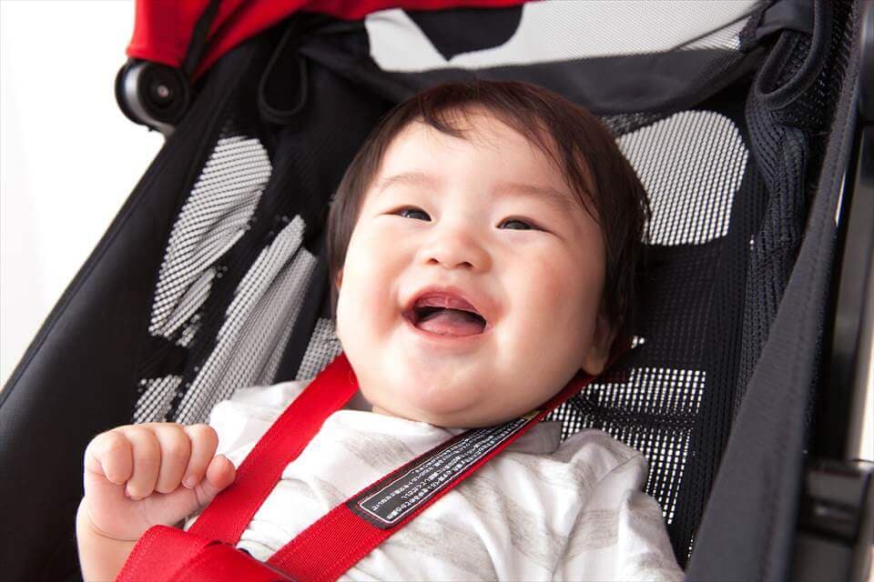 ベビーカーに乗って笑う赤ちゃん