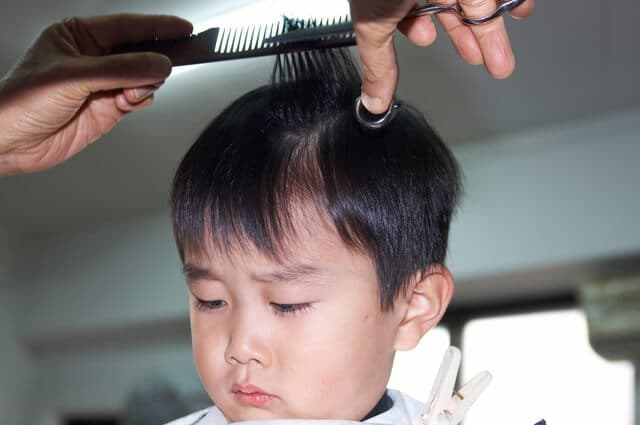 美容院で髪の毛を切る男の子