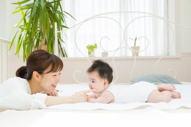 ベッドの上で遊ぶ赤ちゃんと母親