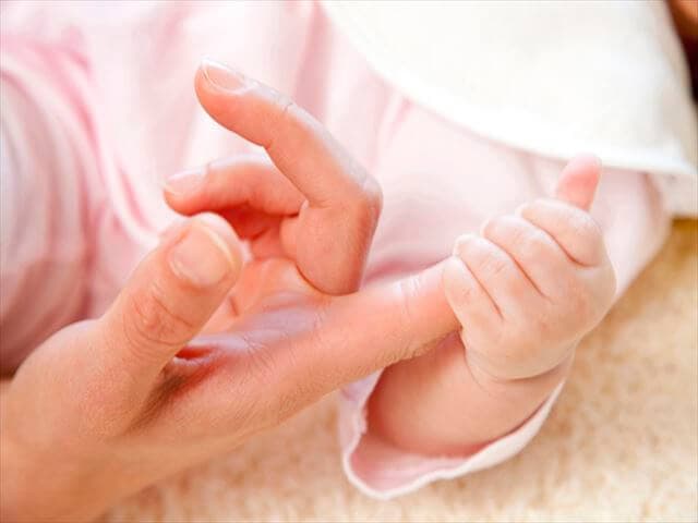ママの指をにぎる赤ちゃん